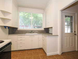 Kitchen featuring decorative backsplash, white cabinets, a healthy amount of sunlight, and sink