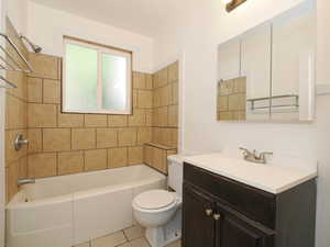 Full bathroom with toilet, tiled shower / bath combo, vanity, and tile patterned flooring