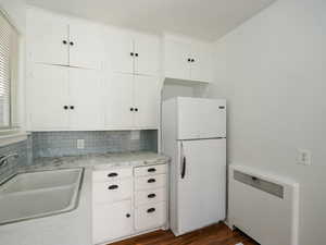 Kitchen featuring sink, white cabinetry, radiator, white fridge, and dark wood-type flooring