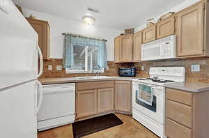 Kitchen with decorative backsplash, sink, white appliances, and light tile patterned floors