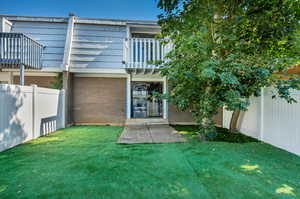 Backyard with balcony, mature trees, and artificial grass