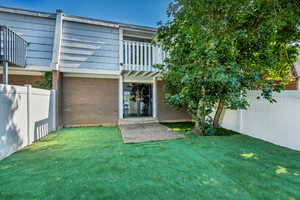 Backyard with balcony, mature trees, and artificial grass