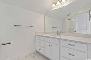 Bathroom with vanity, tile patterned floors, and vaulted ceiling