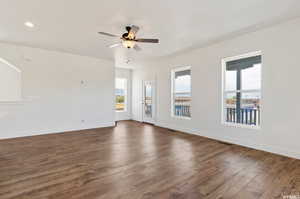 Unfurnished living room featuring ceiling fan and dark hardwood / wood-style flooring