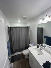 Bathroom featuring hardwood / wood-style floors, vanity, a textured ceiling, and toilet