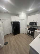 Kitchen with white cabinetry, stainless steel appliances, and light wood-type flooring