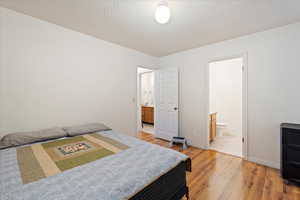 Bedroom featuring a textured ceiling, light hardwood / wood-style floors, and ensuite bath