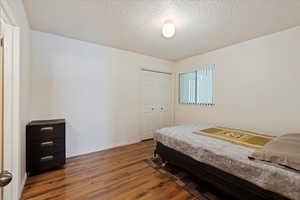 Bedroom with a closet, wood-type flooring, and a textured ceiling