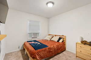 Bedroom with cooling unit and light colored carpet