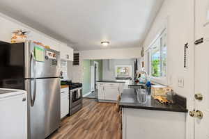 Kitchen featuring light hardwood / wood-style flooring, kitchen peninsula, white cabinets, stainless steel appliances, and sink