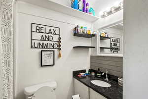 Bathroom featuring vanity, backsplash, and toilet