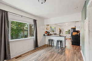 Kitchen featuring a breakfast bar, kitchen peninsula, white cabinets, light hardwood / wood-style floors, and sink