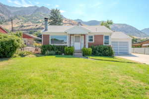 View of front of house with a garage, a front lawn, and a mountain view