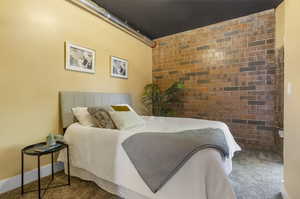 Carpeted bedroom with brick wall