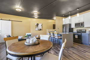 Dining room with dark hardwood / wood-style floors and a barn door