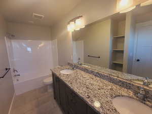 Full bathroom featuring tile patterned floors, dual vanity, bathing tub / shower combination, and toilet