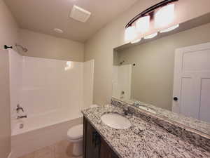 Full bathroom featuring tile patterned flooring, toilet, vanity, and shower / tub combination