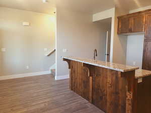 Kitchen featuring light stone countertops, hardwood / wood-style floors, and a breakfast bar