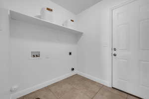 Laundry area with hookup for a gas dryer, light tile patterned flooring, electric dryer hookup, and washer hookup