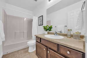 Full bathroom featuring shower / tub combo with curtain, vanity, tile patterned floors, and toilet