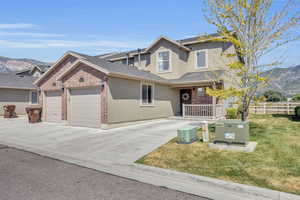 View of front of property with a mountain view, central air condition unit, a garage, and a front lawn