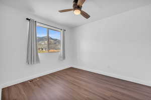 Empty room with a mountain view, dark hardwood / wood-style flooring, and ceiling fan