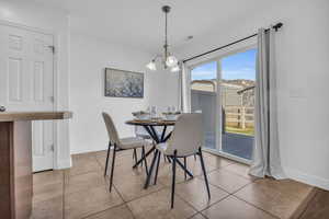 Dining room with a healthy amount of sunlight, light tile patterned floors, and a chandelier