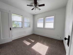 Carpeted spare room featuring ceiling fan