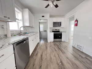 Kitchen featuring light wood-type flooring, white cabinets, ceiling fan, appliances with stainless steel finishes, and sink