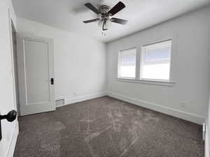 Spare room with dark colored carpet and ceiling fan