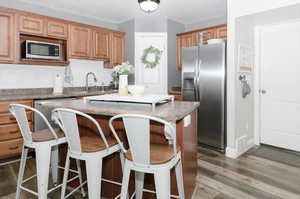 Kitchen with a center island, dark hardwood / wood-style floors, stainless steel appliances, decorative backsplash, and sink