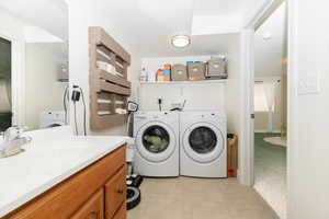 Washroom featuring washing machine and clothes dryer, sink, and light tile patterned flooring