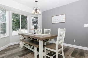 Dining space with dark hardwood / wood-style floors, a healthy amount of sunlight, and an inviting chandelier