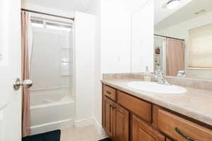 Bathroom with vanity, shower / bathtub combination with curtain, and tile patterned flooring