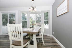 Dining area with dark wood-type flooring and a chandelier