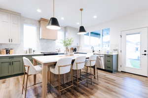 Kitchen featuring a kitchen island, tasteful backsplash, light wood-type flooring, and stainless steel appliances