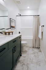 Full bathroom with tile patterned flooring, shower / bath combo with shower curtain, toilet, and vanity