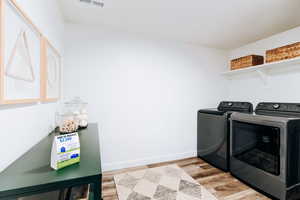 Basement Laundry room with washing machine and clothes dryer and light hardwood / wood-style flooring