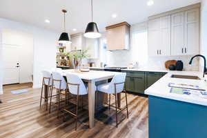 Kitchen with light wood-type flooring, a center island, backsplash, hanging light fixtures, and sink