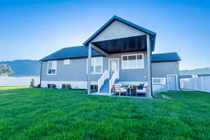 Rear view of property featuring an outdoor living space, a patio, a mountain view, and a lawn