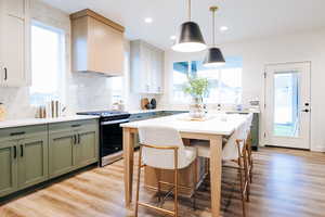 Kitchen featuring gas range, light hardwood / wood-style flooring, a healthy amount of sunlight, and tasteful backsplash