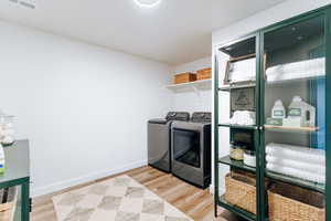 Basement Laundry room with light hardwood / wood-style flooring and washer and clothes dryer