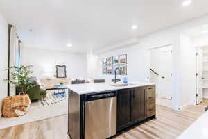 Kitchen featuring light hardwood / wood-style floors, sink, dishwasher, and an island with sink