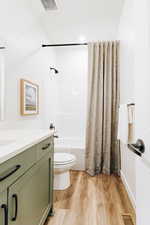 Full bathroom featuring hardwood / wood-style flooring, shower / bath combination with curtain, toilet, and vanity