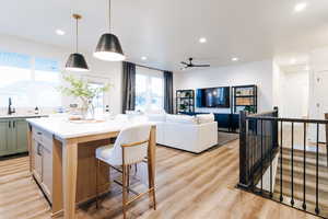 Kitchen with a center island, ceiling fan, light hardwood / wood-style floors, decorative light fixtures, and sink