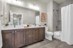 Full bathroom with tile patterned flooring, shower / bath combo, toilet, and dual bowl vanity