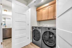 Laundry room featuring cabinets, independent washer and dryer, and light hardwood / wood-style flooring