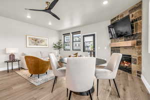 Dining room featuring a fireplace, light hardwood / wood-style flooring, and ceiling fan