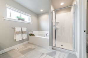 Bathroom featuring shower with separate bathtub, tile patterned flooring, and toilet