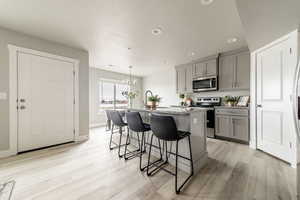 Kitchen featuring pendant lighting, light hardwood / wood-style floors, light stone countertops, and gray cabinetry